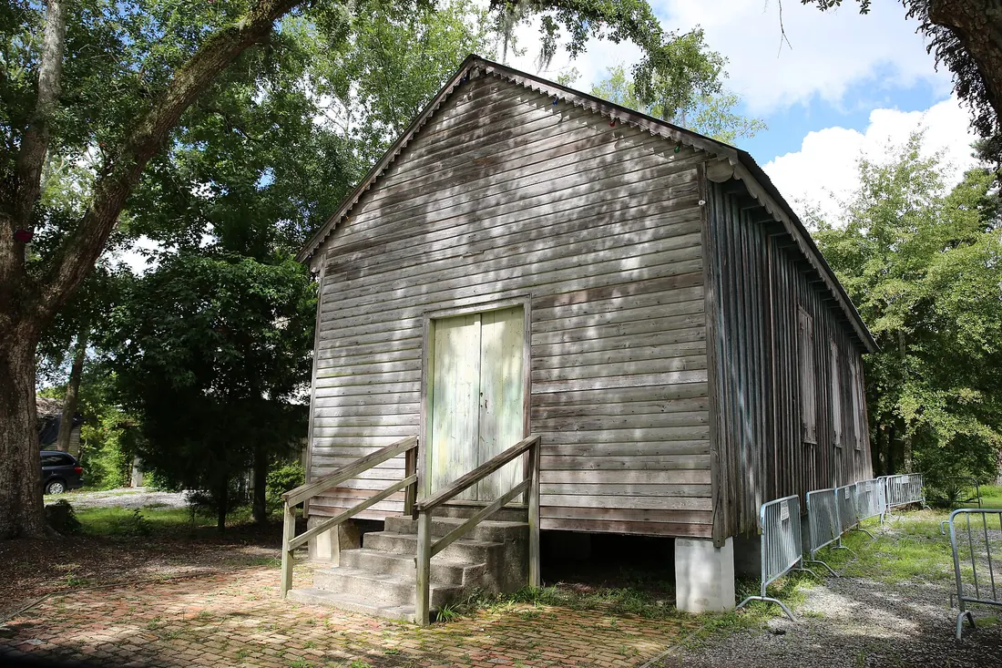 Weathered wooden Dew Drop Hall with steps and double doors under large shade trees