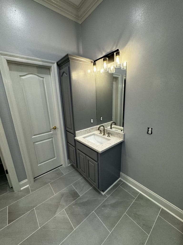Sink with a Mirror beside a close door - Turnkey Bath Remodel