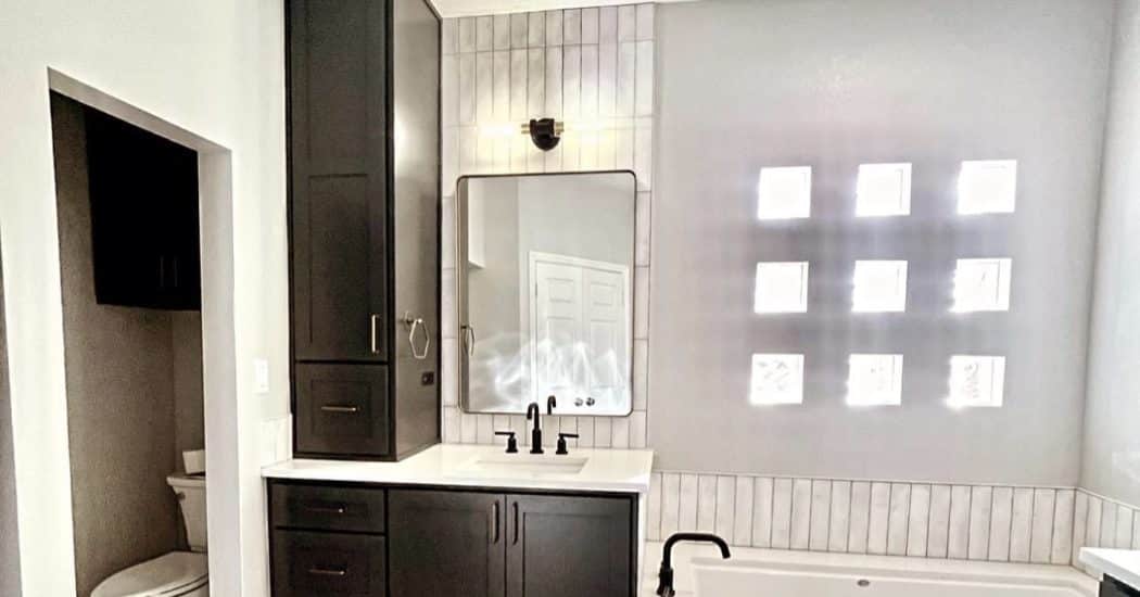 Remodeled New Orleans bathroom with a dark vanity and a drop-in tub