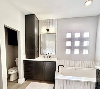 Remodeled New Orleans bathroom with a dark vanity and a drop-in tub