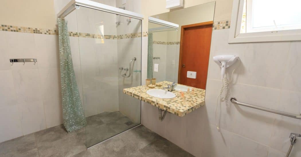 Spacious accessible bathroom with a barrier-free glass shower and grab bars in a New Orleans home