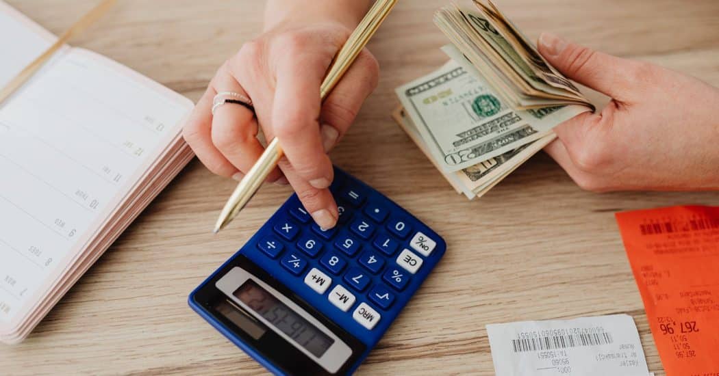 A calculator, cash, receipts, and a planner on a table as a homeowner works out a bathroom remodel budget