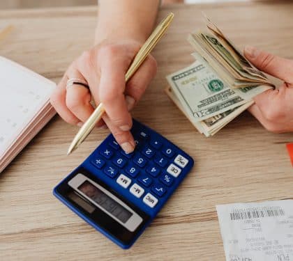 A calculator, cash, receipts, and a planner on a table as a homeowner works out a bathroom remodel budget